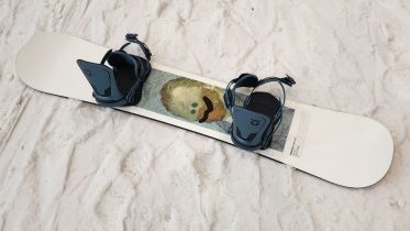 Nidecker Tape Deck snowboard resting on snow with Union Neo bindings